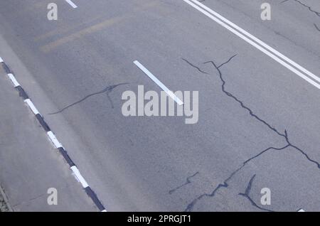 Danneggiato cattiva strada asfaltata con buche. Riparazione delle patch di asfalto. Bad asfalto rotto pericolose strada per automobili, crepe e buche in asfalto Foto Stock