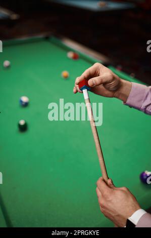 Closeup uomo giocatore di biliardo strofinando cue con gesso, gioco snooker in piscina sala giochi Foto Stock