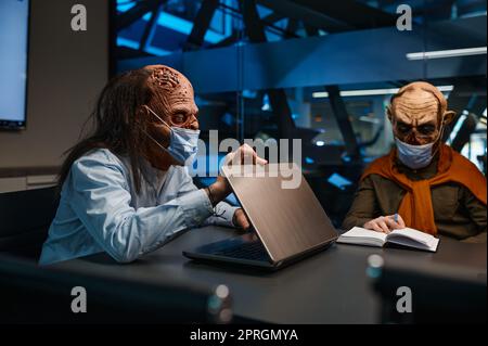 Uomini d'affari zombie che indossano maschera facciale chattando alla conferenza d'affari. Incontro di lavoro durante il concetto di pandemia Foto Stock