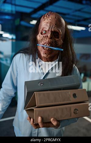 Zombie dipendente che trasporta la pila di raccoglitori cartella. Un lavoratore che lavora in ufficio può gestire un'enorme quantità di file cartacei. Lavoro straordinario, concetto di workaholic e di scadenza Foto Stock
