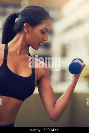 Sei forte solo come credi di essere, una giovane donna che lavora con i manubri. Foto Stock