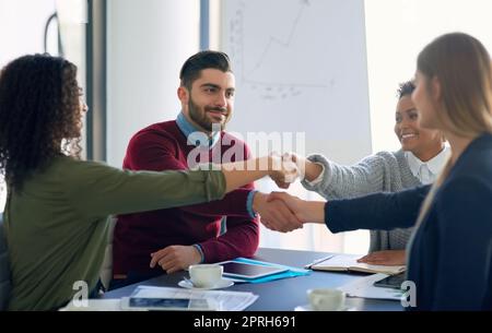 Un gruppo di giovani imprenditori che si riuniscono per realizzare la propria visione di squadra, che si stringono le mani durante una riunione d'ufficio. Foto Stock