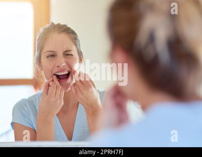 Sbarazzarsi di tutta la placca, una giovane donna che le gallina i denti in uno specchio. Foto Stock