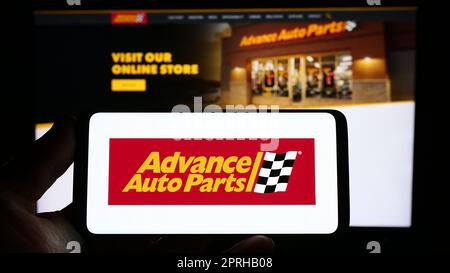 Persona che tiene lo smartphone con il logo di US Automotive società Advance Auto Parts Inc. Sullo schermo di fronte al sito web. Messa a fuoco sul display del telefono. Foto Stock