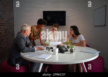 La tavola rotonda delle idee: Un gruppo di colleghi che lavora tardi in un ufficio. Foto Stock