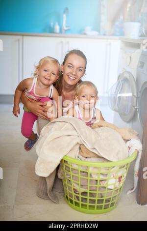 Theyre una famiglia piena di glee. Ritratto di una madre e delle sue figlie che si divertono mentre fanno i lavori di casa. Foto Stock