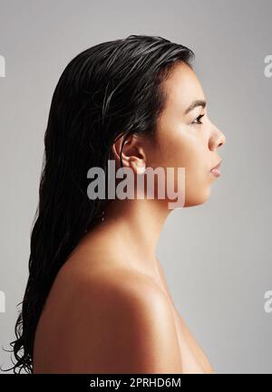 Naturalmente bello da qualsiasi angolazione. Studio di una giovane donna con capelli bagnati che si posano su uno sfondo grigio. Foto Stock