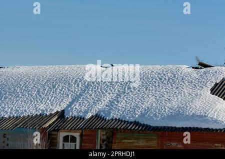 un blocco di ghiaccio pende dal tetto della casa Foto Stock