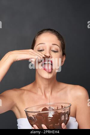 Ceneri un amante del cioccolato. Studio girato di una giovane donna attraente che è tentato da qualcosa di dolce. Foto Stock