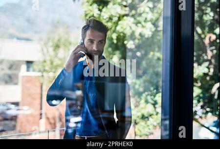 Parliamo lavoro. Un giovane uomo d'affari che parla al telefono al di fuori di un ufficio. Foto Stock