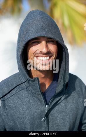 Felice hunk con una felpa con cappuccio. Ritratto di bel giovane uomo sorridente mentre indossa una felpa con cappuccio Foto Stock