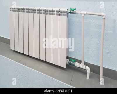 Batteria bianca per radiatore in alluminio moderno per riscaldamento ad acqua calda, sullo sfondo di una parete all'interno di un appartamento o di un ufficio Foto Stock