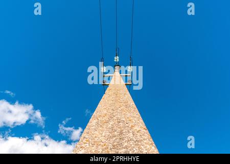 Palo della linea di alimentazione con cavi elettrici sullo sfondo del cielo Foto Stock