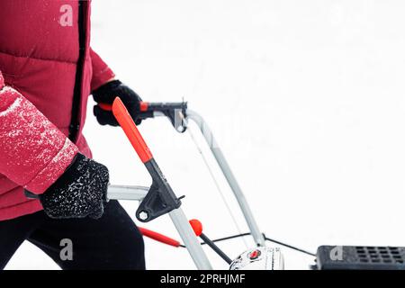 Uomo che usa una motoslitta rossa all'aperto. Rimozione della neve vicino alla casa dal cortile Foto Stock