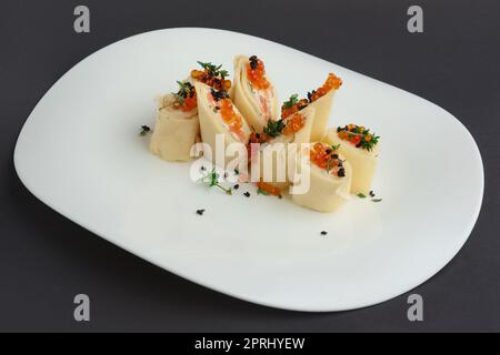 Frittelle con salmone e caviale sulla grande piastra bianca Foto Stock