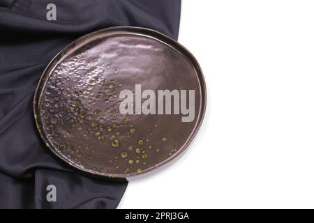 Cerchio nero vuoto moderno piatto in ceramica con tovaglia in seta su sfondo bianco , Vista dall'alto Foto Stock