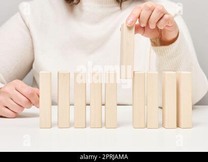 Blocchi di legno sul tavolo, la mano di una donna ne tiene uno. Il concetto di trovare dipendenti unici e di talento Foto Stock