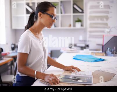 Guardando oltre il suo primo articolo di moda. Un giovane stilista al lavoro Foto Stock