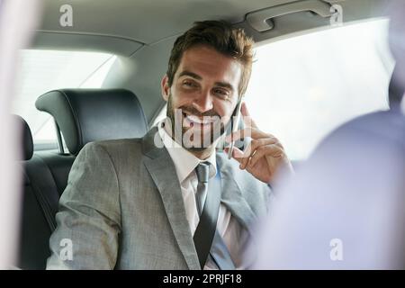 In viaggio d'affari. Un bel giovane uomo d'affari che parla sul cellulare sul sedile posteriore di un'auto. Foto Stock