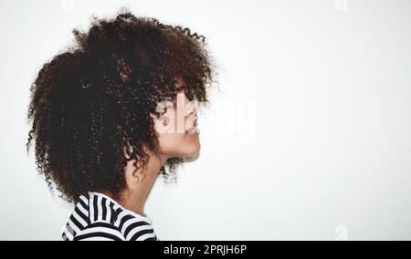 Ricci davvero carini. Profilo di una giovane donna attraente in posa su uno sfondo grigio in studio. Foto Stock