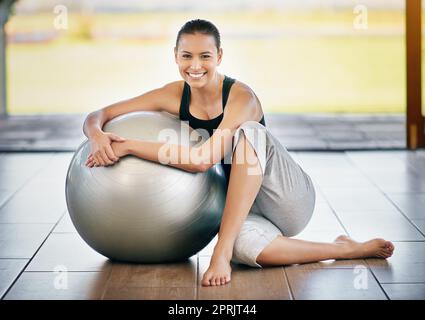 Sentirsi rinfrescati dopo un allenamento. Ritratto completo di una giovane donna seduta contro la palla da ginnastica. Foto Stock