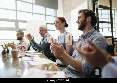 Un gruppo di uomini d'affari applaudono durante una riunione in seno al consiglio di amministrazione. Foto Stock