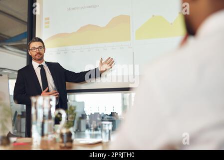 Delineare una nuova politica fiscale aziendale: Un dirigente che presenta una presentazione su uno schermo di proiezione a un gruppo di colleghi in una sala riunioni. Foto Stock