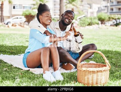 Coppia al picnic in giardino, donna nera e bottiglia di birra insieme. Giovane uomo africano, che beve alcolici e una ragazza felice. Natura all'aperto, parco in città e tempo di relazione d'amore insieme Foto Stock