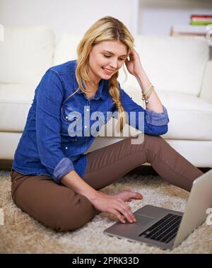 Per recuperare un po' di informazioni sui social media. Una giovane donna che usa il suo notebook a casa. Foto Stock