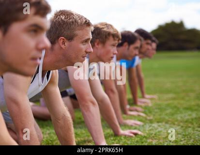 La strada sudata al successo. una fila di giovani sportivi che fanno i push-up Foto Stock