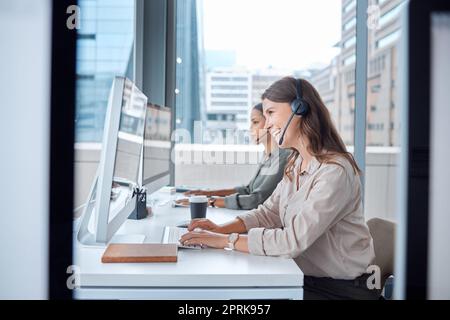 Im più che felice di aiutare. due giovani donne che lavorano nel call center nel loro ufficio Foto Stock