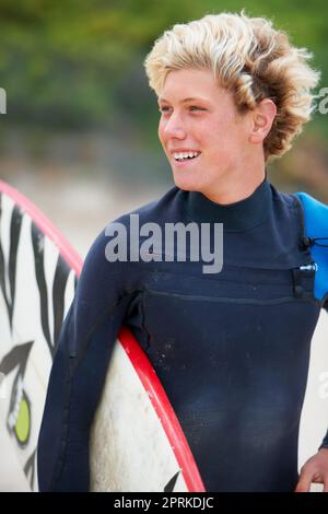 Facciamo questo. un giovane surfista sulla spiaggia che porta la sua tavola Foto Stock