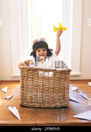 Il tempo vola quando youre avere divertimento. un adorabile ragazzino seduto a giocare in un cesto tra i getti di carta Foto Stock