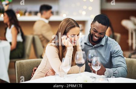 Il suo evidente theyre nell'amore. una giovane coppia affettuosa gustando un po' di vino insieme in un ristorante Foto Stock