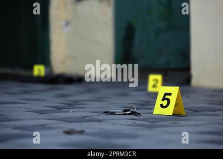 Prova con indicatore CSI giallo per la numerazione delle prove sul cortile interno in serata. Concetto del processo di indagine sulla scena del crimine Foto Stock