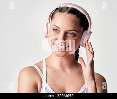 La musica è il buon tipo di distrazione. Studio di una giovane donna sportiva che indossa le cuffie su sfondo bianco Foto Stock