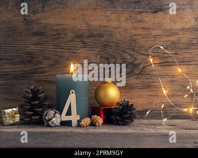 Candela del quarto Avvento bruciature, coni di pino e decorazione di Natale su legno con luci di Natale Foto Stock