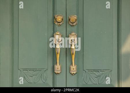 Maniglie delle portiere il vecchio ottone sulla porta verde era usato a. chiudere o aprire lo sportello Foto Stock