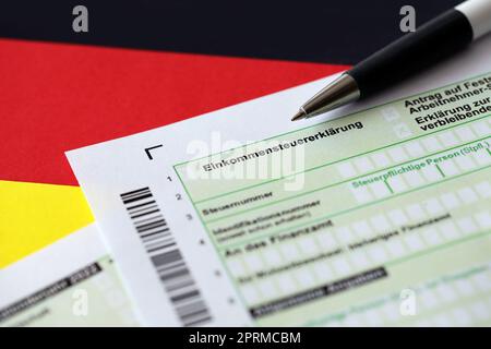 Modulo di dichiarazione della dichiarazione della tassa sul reddito annuale tedesca con penna a bandiera a primo piano. Il concetto di rendicontazione fiscale in Germania e in Europa Foto Stock