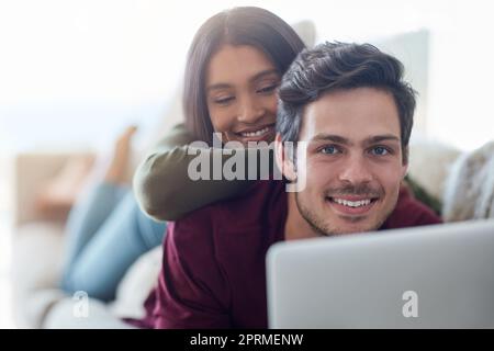 Le ceneri mi hanno sempre fatto le spalle. Una giovane coppia affettuosa che usa il computer portatile mentre si sdraiava sul divano a casa. Foto Stock