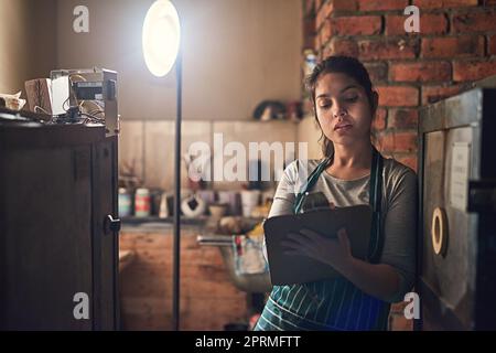 Fare qualche amministratore intorno al suo workshop. Un giovane imprenditore scrivere su una clipboard in un workshop. Foto Stock