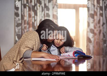 Mamma, im cercando di lavorare qui. Una madre che guarda sua figlia fare i compiti a casa. Foto Stock