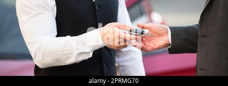 Servizio di parcheggio con parcheggiatore. In piedi vicino alla porta che dà la chiave Foto Stock