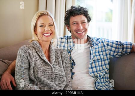 Abbiamo trovato l'amore l'uno nell'altro. Ritratto corto di una coppia matura che si rilassa sul divano a casa. Foto Stock