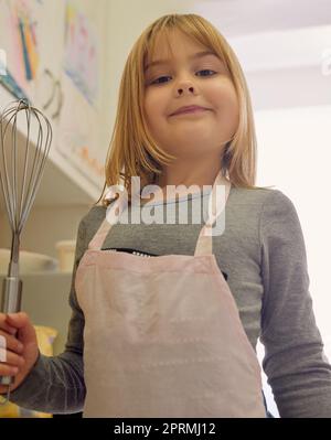 Dove theres una frusta, theres un senso. Ritratto di una bambina che tiene una frusta in piedi in cucina. Foto Stock