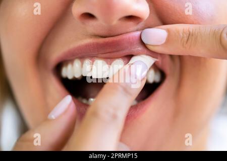 Donna che masticava la nicotina umida tabacco Snus Foto Stock