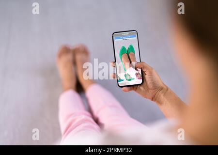 Donna che prova le scarpe con tacco alto virtuali in negozio Foto Stock