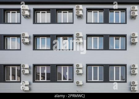 Molti condizionatori d'aria sono appesi alla facciata di un nuovo edificio moderno. Foto Stock