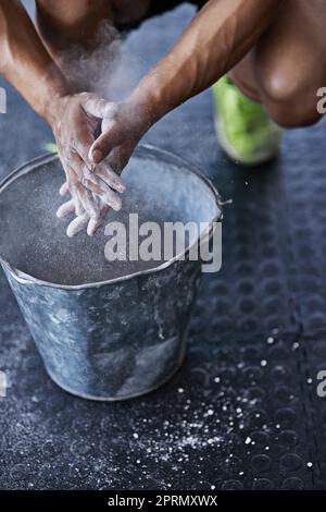 Usate il gesso. Un giovane che mette la polvere di gesso sulle sue mani in palestra. Foto Stock