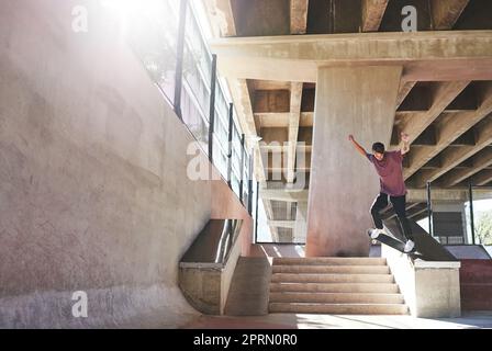 Mantieni il tuo equilibrio. Un giovane che fa trucchi sul suo skateboard allo skatepark. Foto Stock
